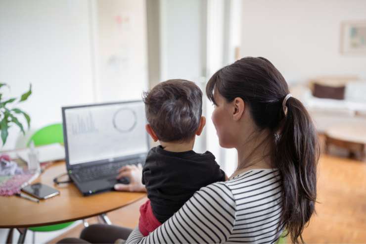 donna di spalle al pc con figlio in braccio