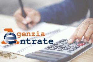 logo agenzia delle entrate e scrivania con persona che scrive e calcolatrice