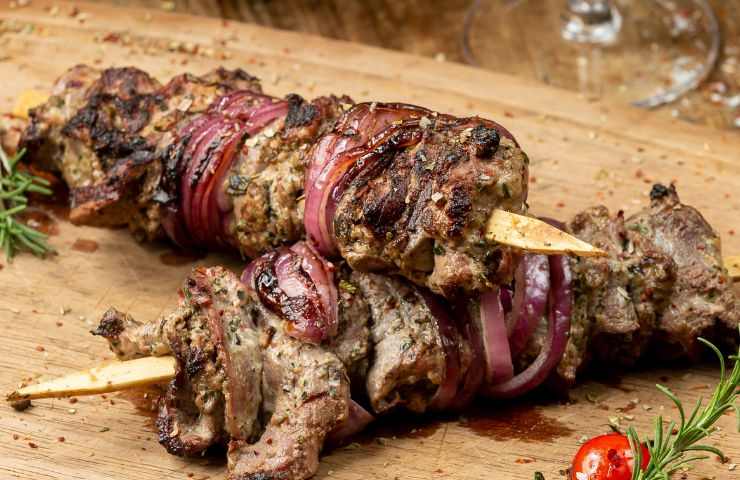 spiedini di carne con cipolle di Trope su tagliere